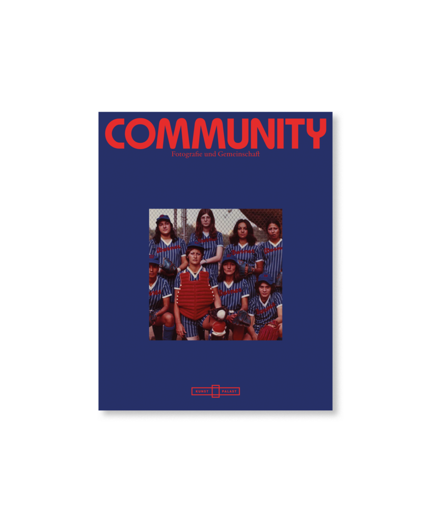 Titelblatt einer Zeitschrift mit dem Titel "COMMUNITY" mit einem alten Foto einer Sportmannschaft in gestreiften Uniformen auf dunkelblauem Hintergrund.